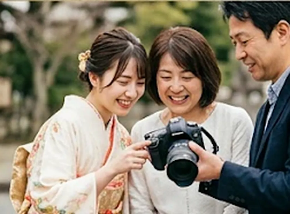 着物姿の娘と家族がカメラの画面を見て笑う様子